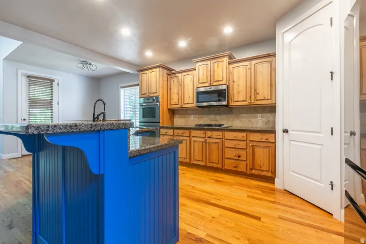 Kitchen featuring a vibrant blue island with a built-in sink and dark faucet, complemented by granite countertops