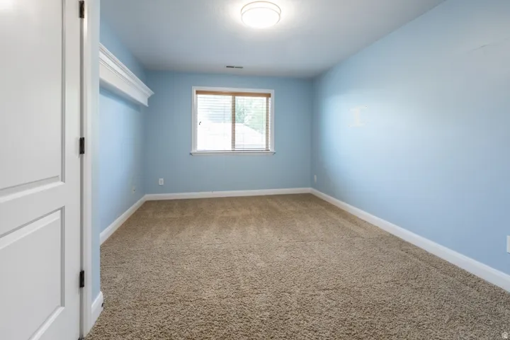 Carpeted room featuring light blue walls, a double-panel interior door, and a window with blinds