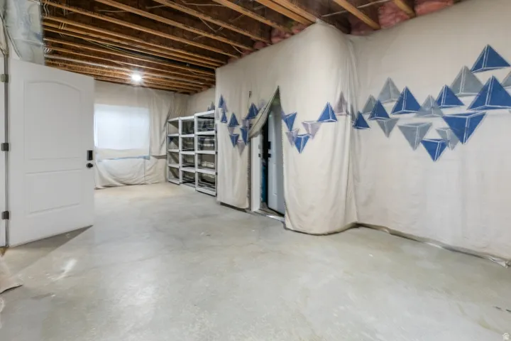 Unfinished basement space featuring exposed ceiling joists, a window, and concrete flooring