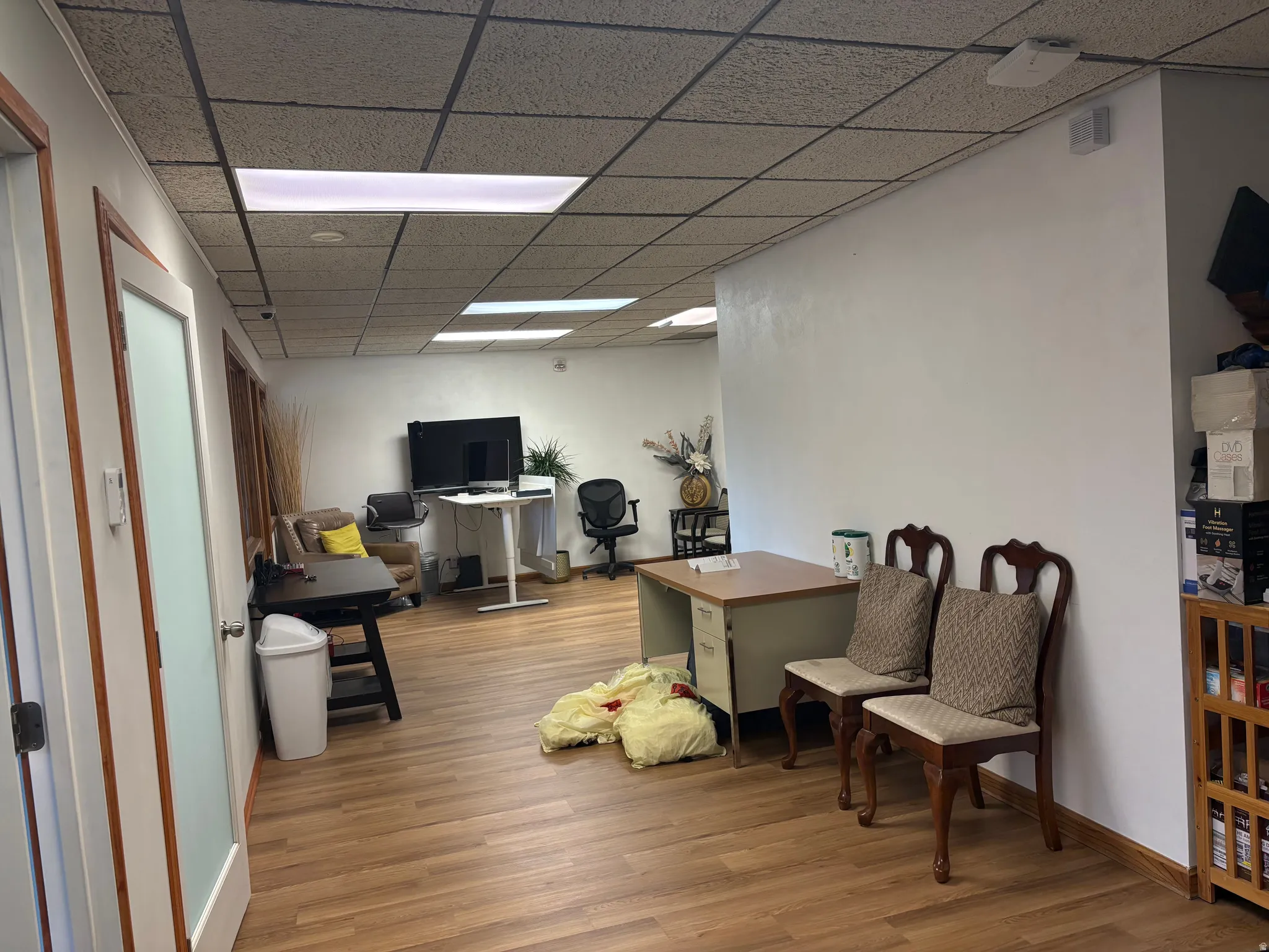 Spacious interior featuring wood-finish flooring, white walls, and a dropped ceiling with recessed lighting