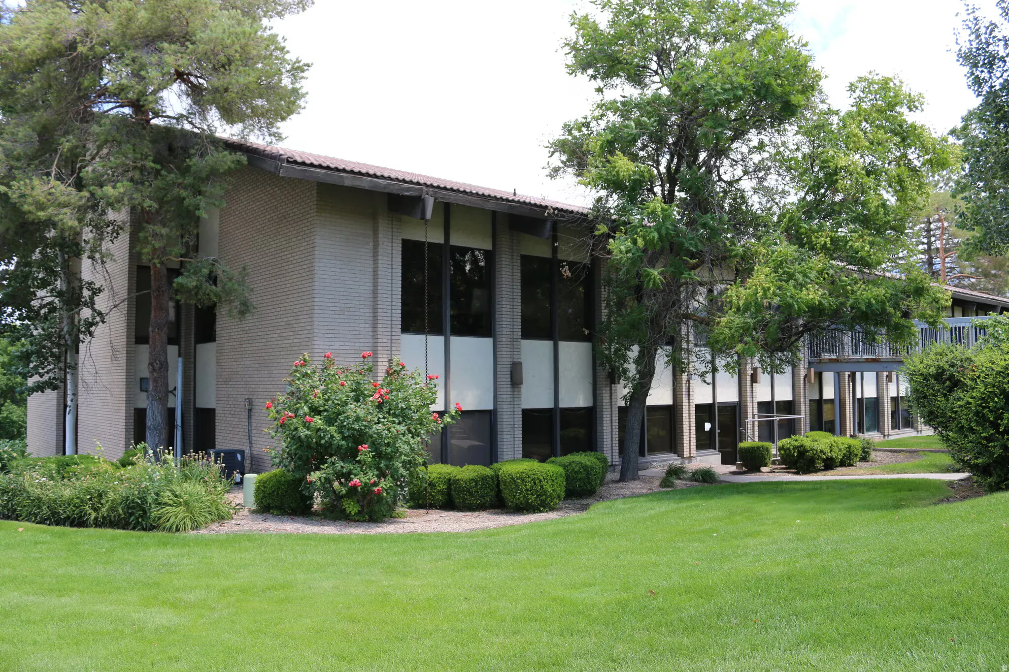 Expansive green space surrounding a two-story building with a brick facade and dark-framed windows