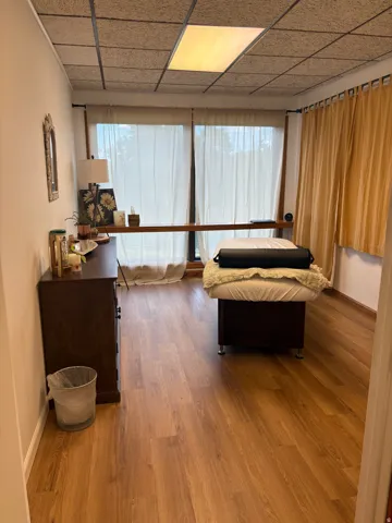 Room featuring wood-finish flooring, a drop ceiling with recessed lighting, and expansive windows fitted with curtain rods
