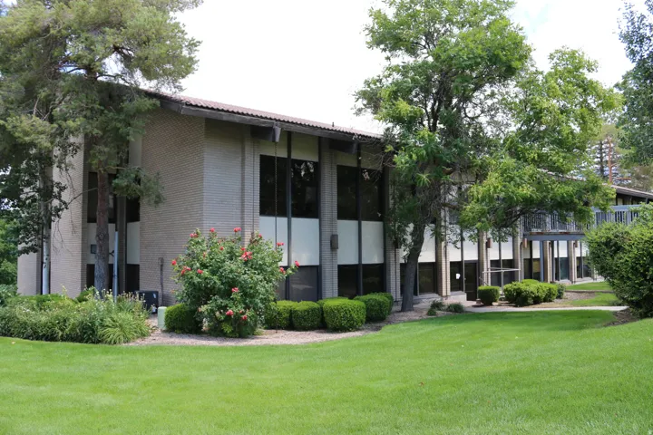 Expansive green space surrounding a two-story building with a brick facade and dark-framed windows