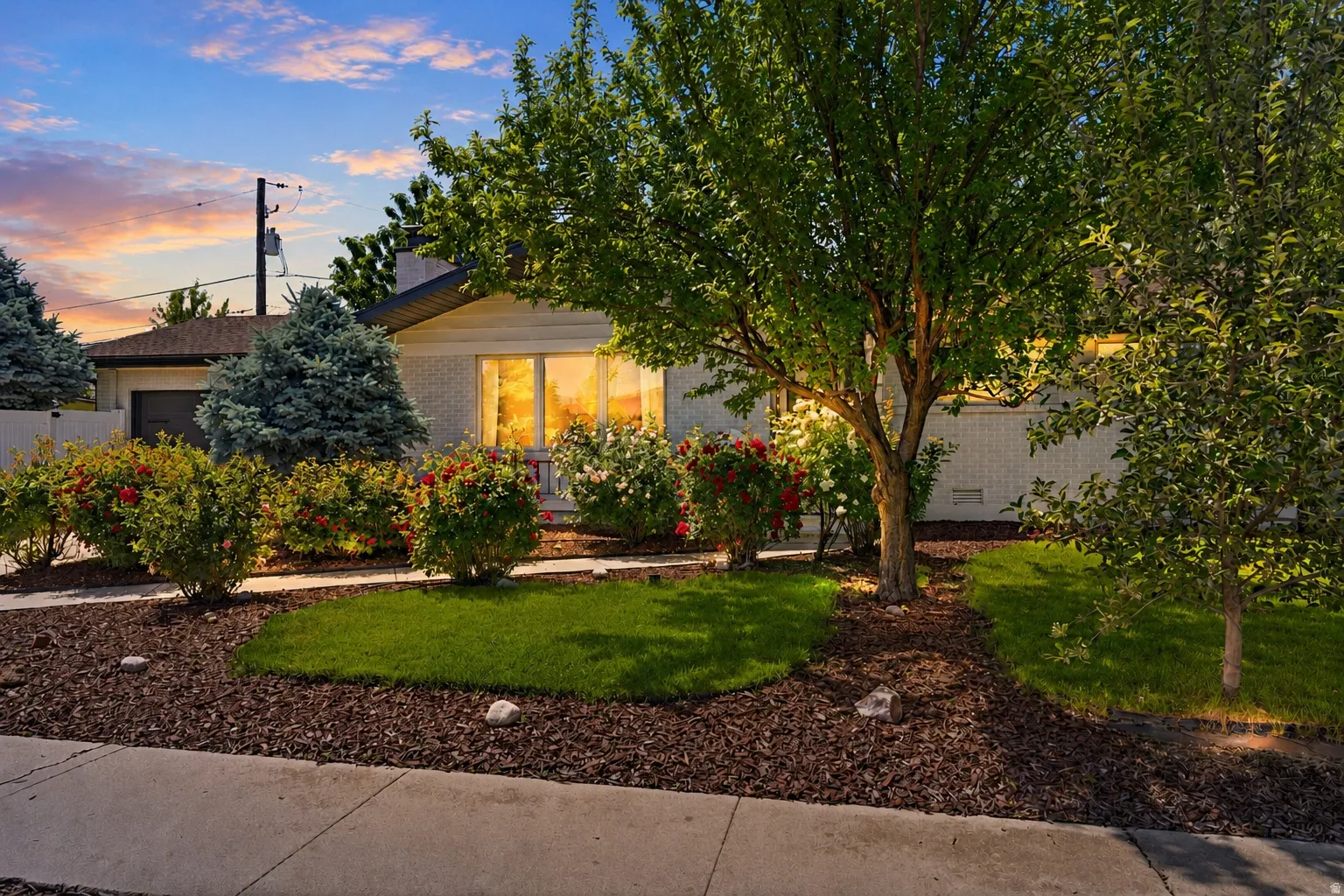 Manicured lawn with mature trees, established shrubbery, and flowering bushes