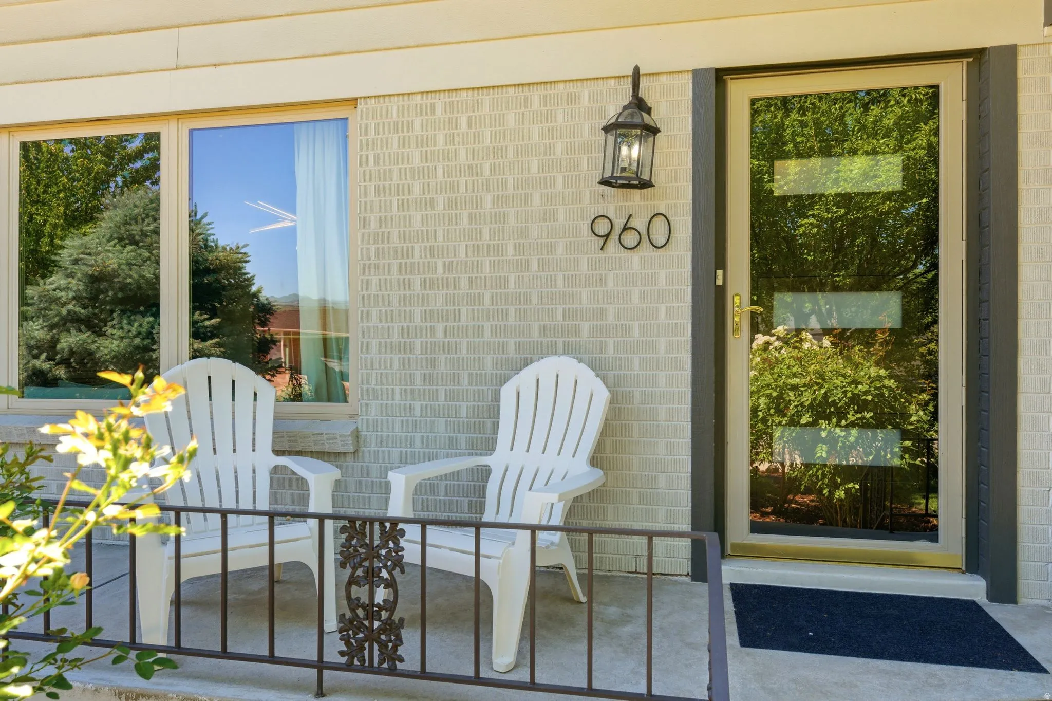 Brick exterior featuring a concrete porch, decorative metal railing, and a contemporary entry door with horizontal glass inserts