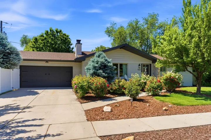 Attached two-car garage, concrete driveway, mature landscaping, and an inviting walkway