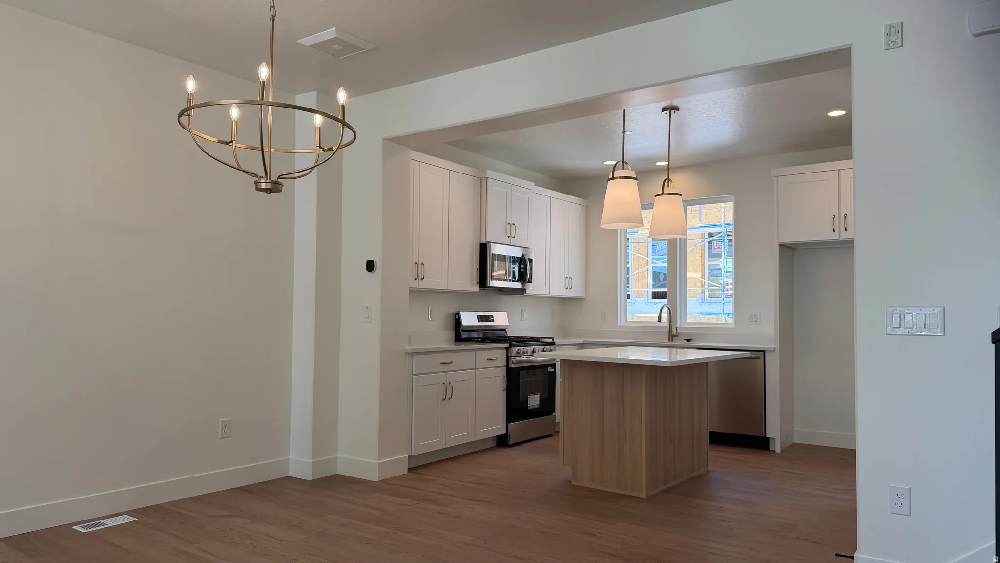 Modern kitchen featuring light cabinetry, stainless steel appliances, and a central island with a light-toned countertop