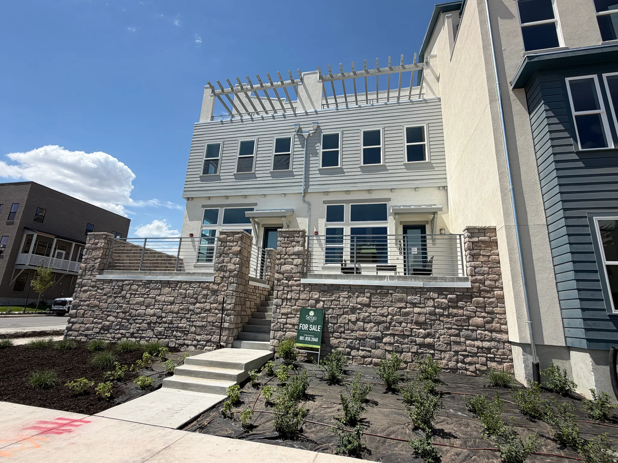 Modern townhouse exterior featuring a stone facade and light-colored siding