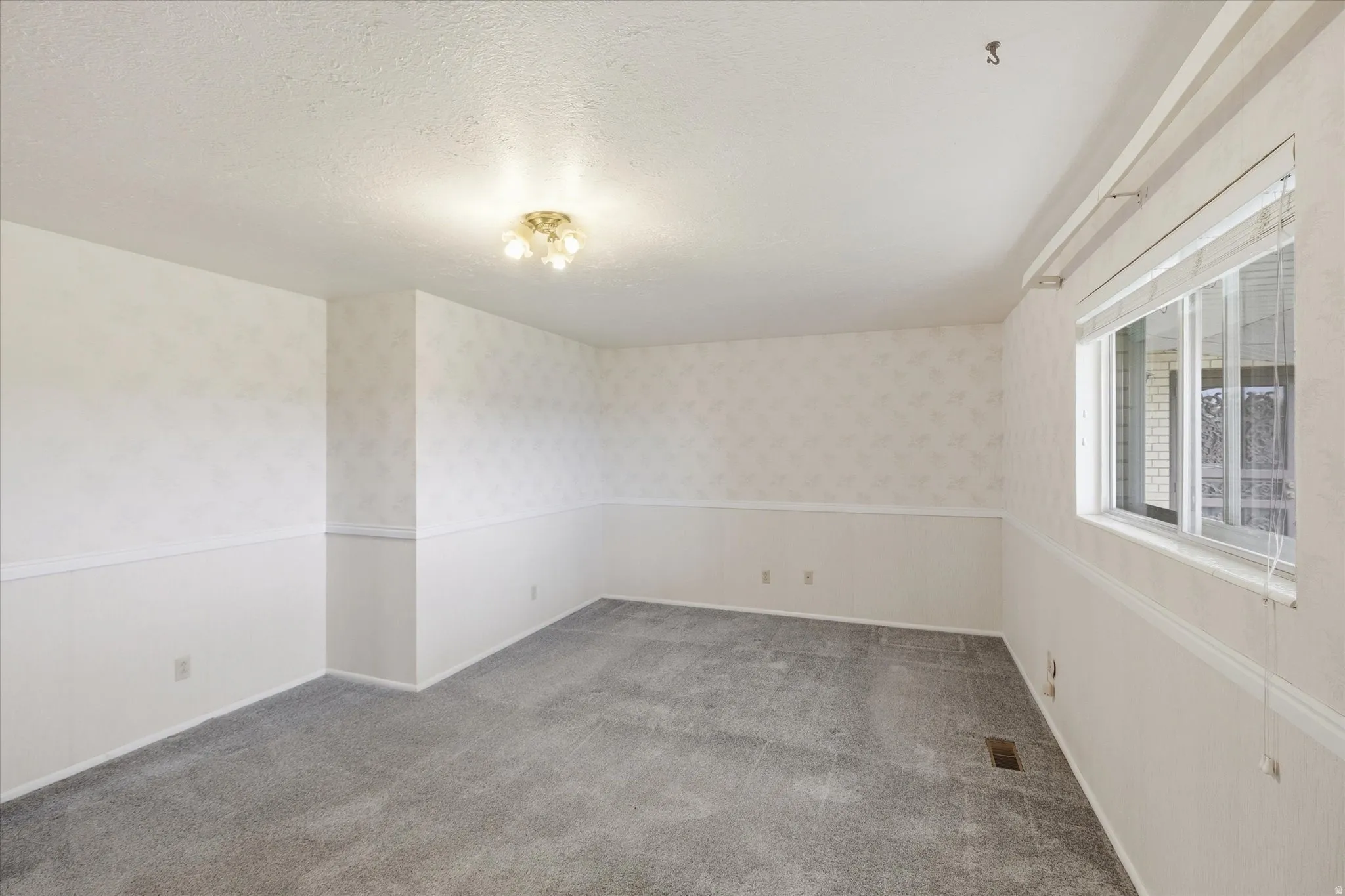 Room featuring neutral carpeting, a dual-pane window with blinds, and a built-in ceiling light fixture