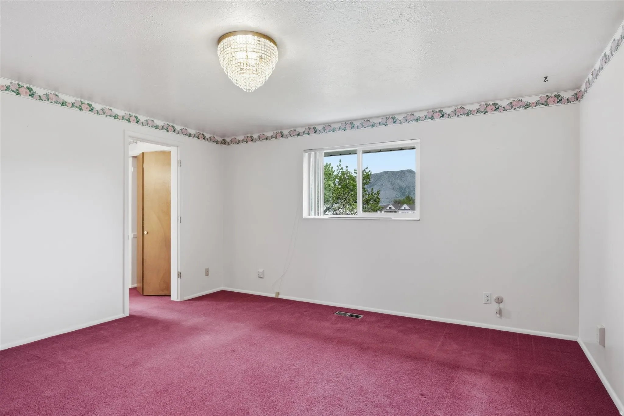 Suite room featuring a crystal chandelier, wall-to-wall carpeting, white painted walls, a window with mountain scenery, and a solid wood door