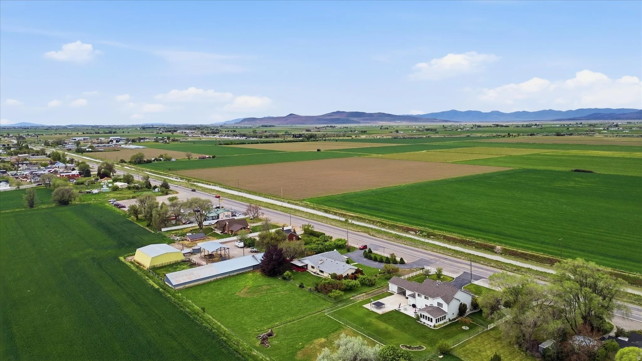 Agricultural setting featuring a main residence with a white exterior, a detached garage, and a large paved patio area