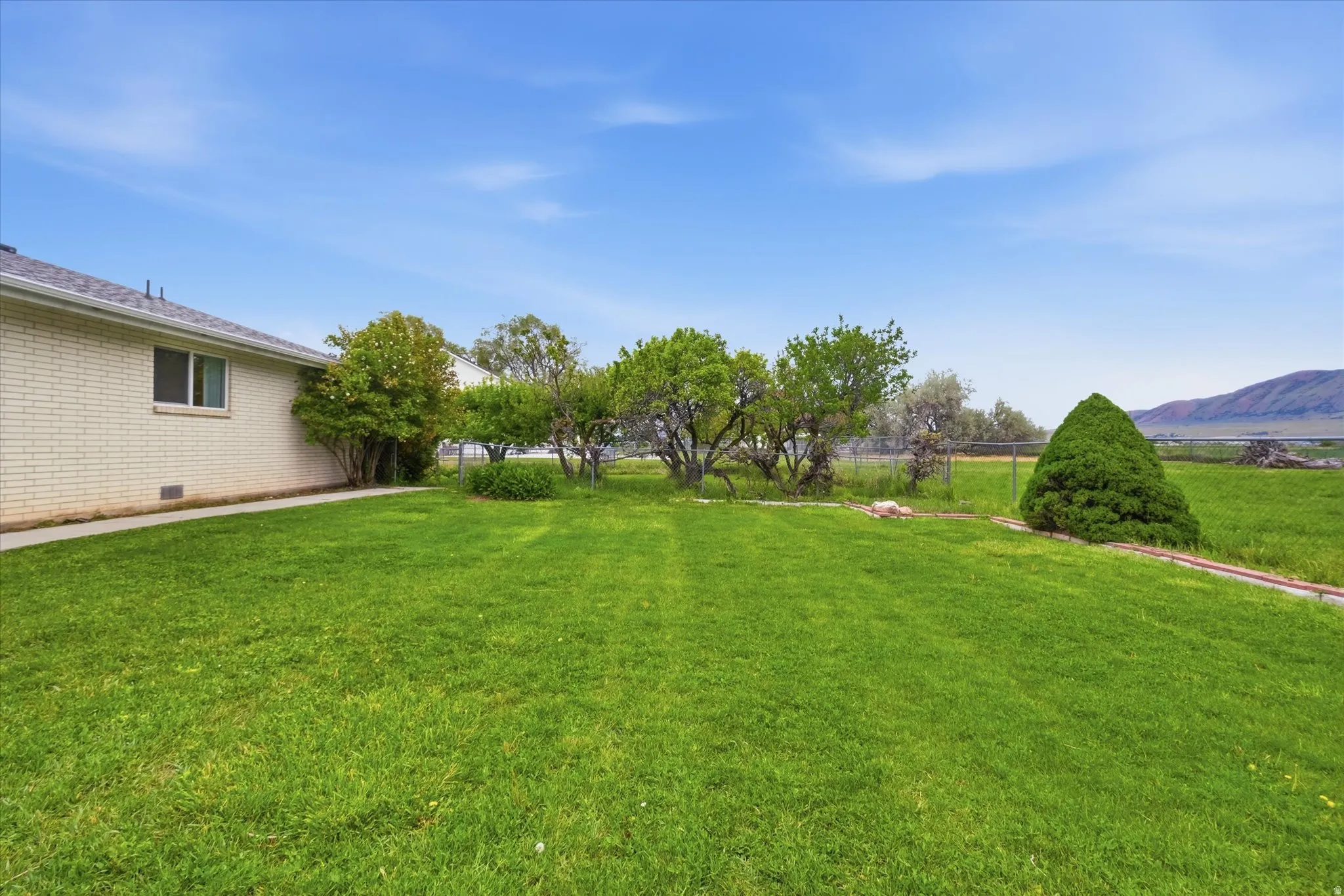 Green lawn with mature trees and a mountain backdrop