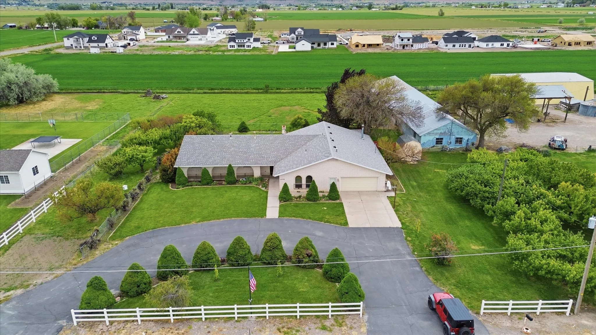 Ranch-style residence featuring a two-car garage, a covered front porch, and a paved driveway with mature landscaping