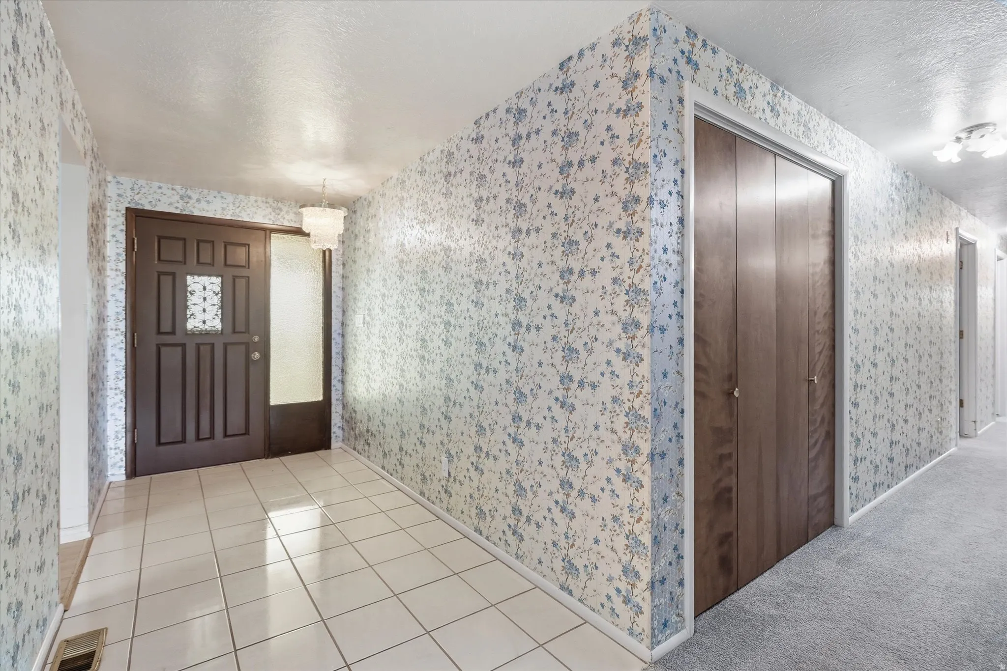 Entryway featuring a dark paneled door with decorative glass, frosted sidelight, and ceramic tile flooring