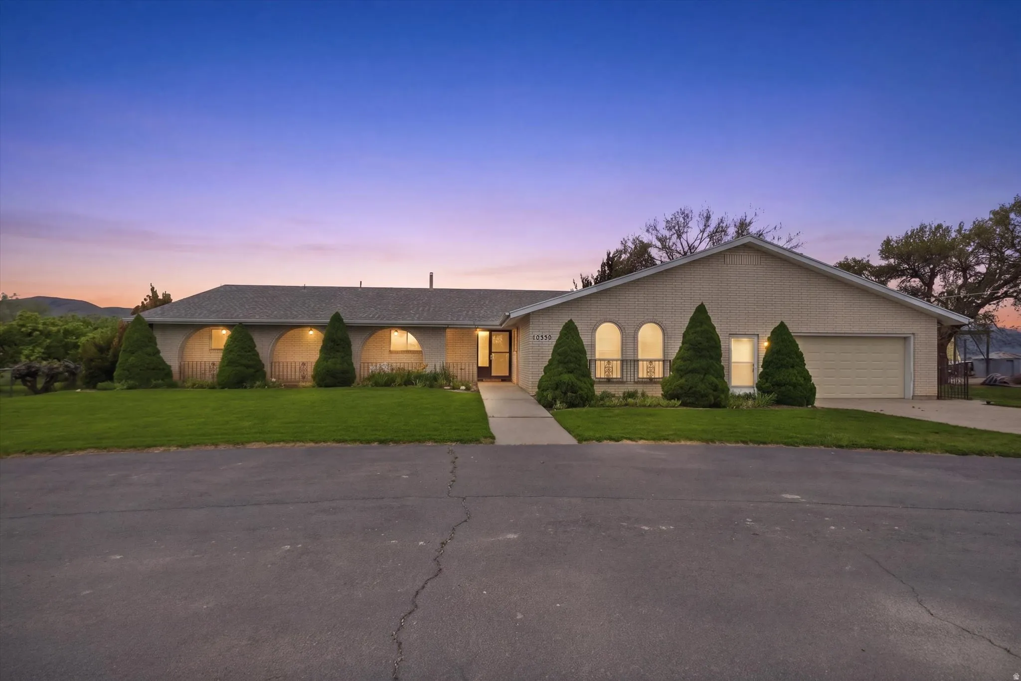 Ranch-style residence featuring a light-colored brick exterior, a covered entryway with three archways, and a two-car garage
