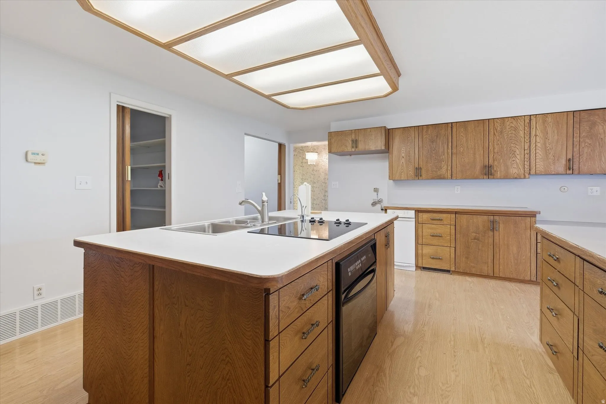 Kitchen featuring an island with integrated cooktop and double basin sink