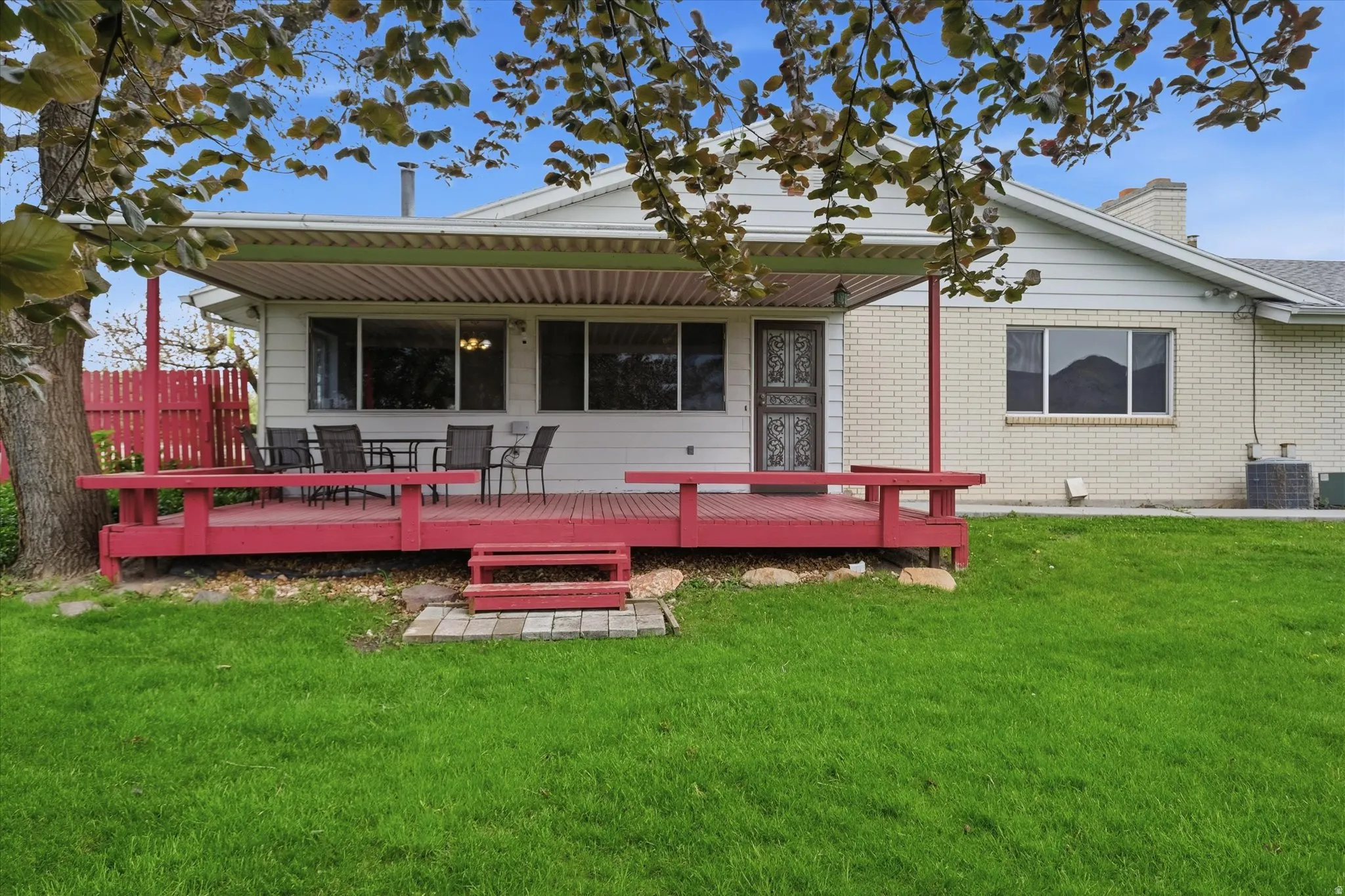 Green lawn with a red wooden deck featuring a covered patio area