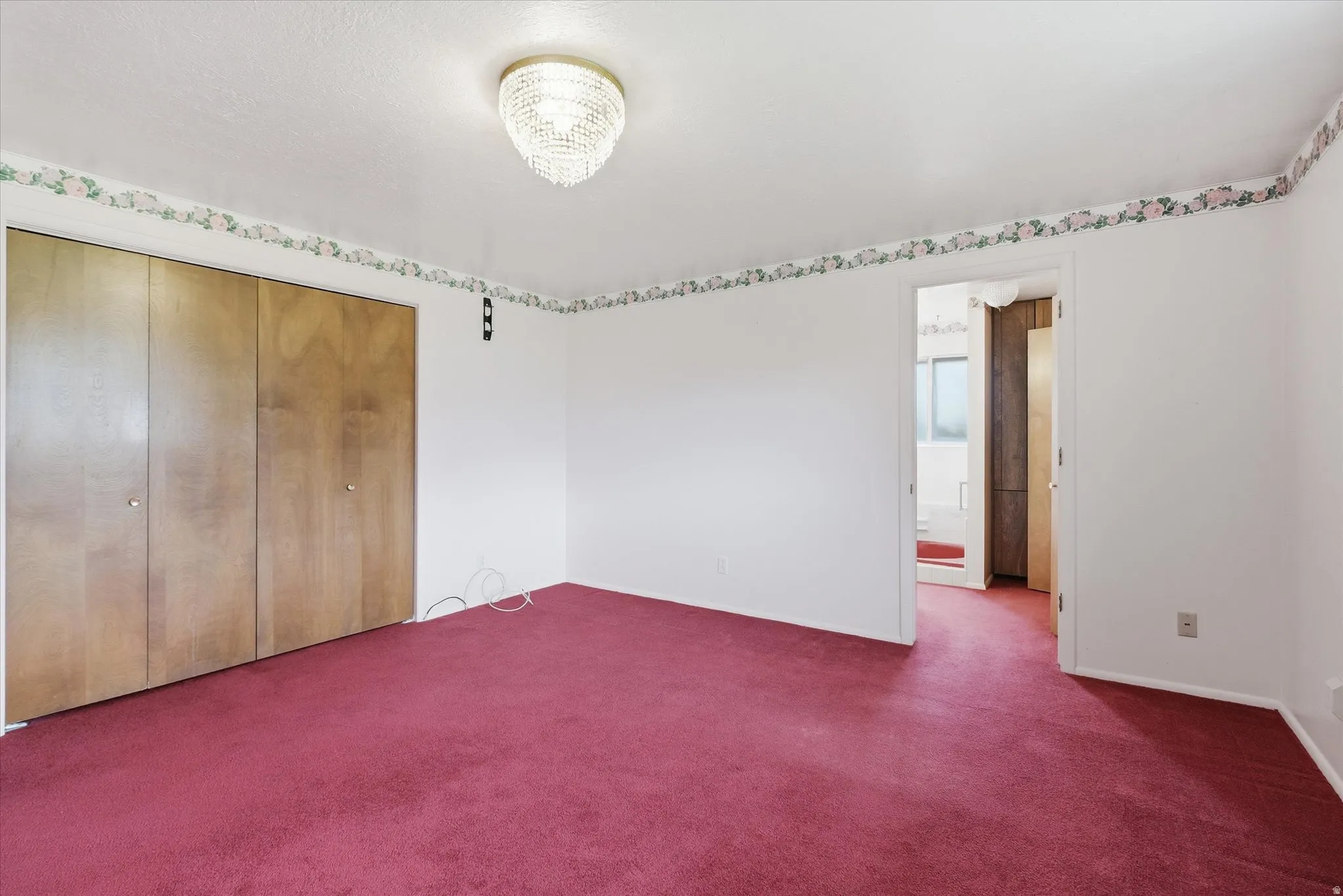 Room featuring wall-to-wall red carpeting, white painted walls, and a floral border detail