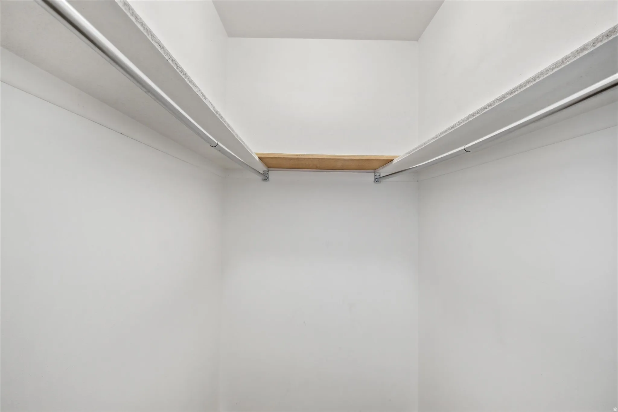 White-painted closet featuring built-in shelving and hanging rods