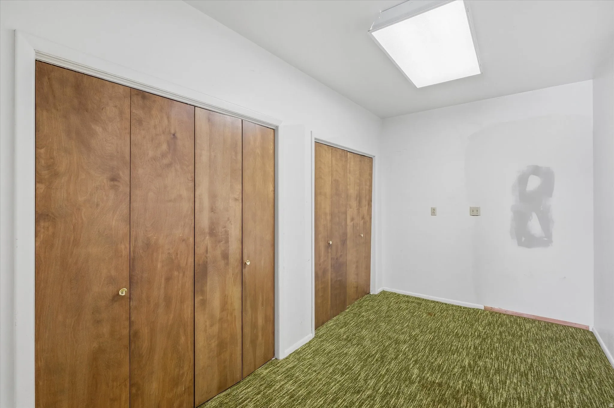 Two sets of wood-finish bi-fold closet doors with brass knobs