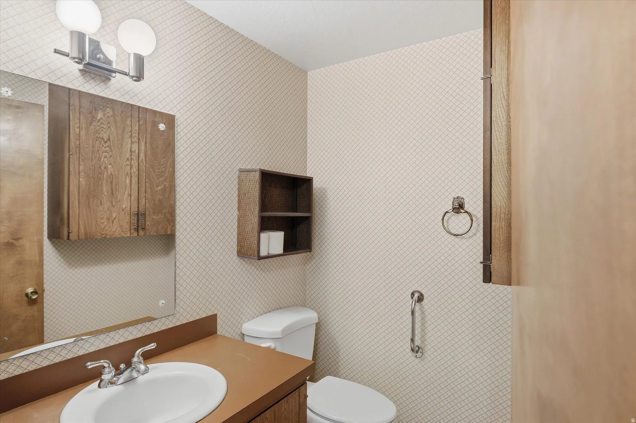 Bathroom featuring a vanity with an integrated sink, wall-mounted mirror, and overhead double light fixture