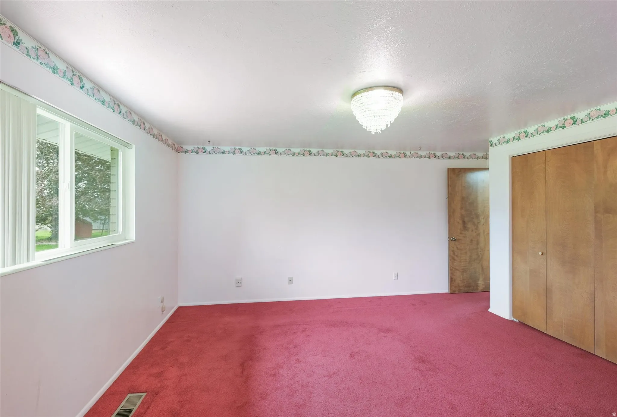 Room featuring red carpeting, white walls, and a decorative ceiling light fixture