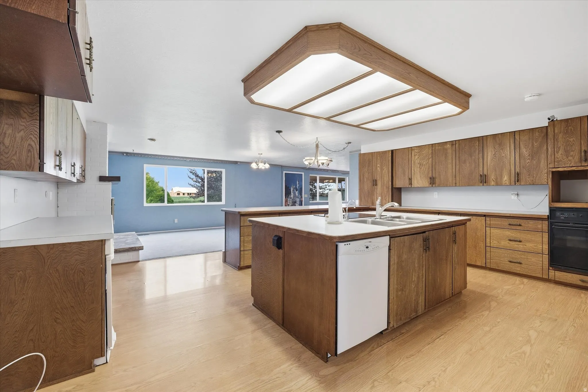 Kitchen featuring a dual-basin sink, light wood-finish cabinetry, and a built-in dishwasher