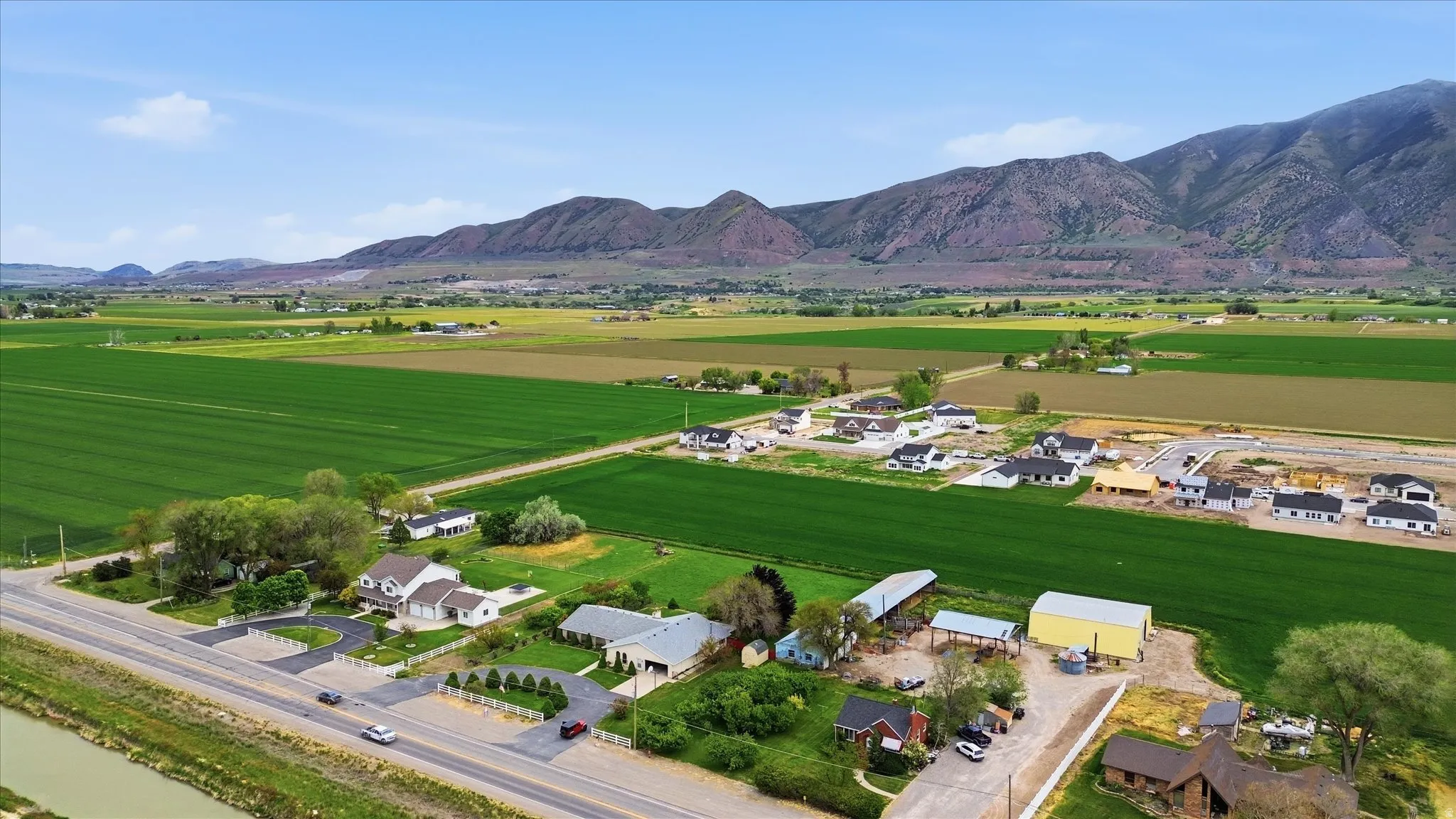 Agricultural fields surrounding residential properties with distant mountain ranges