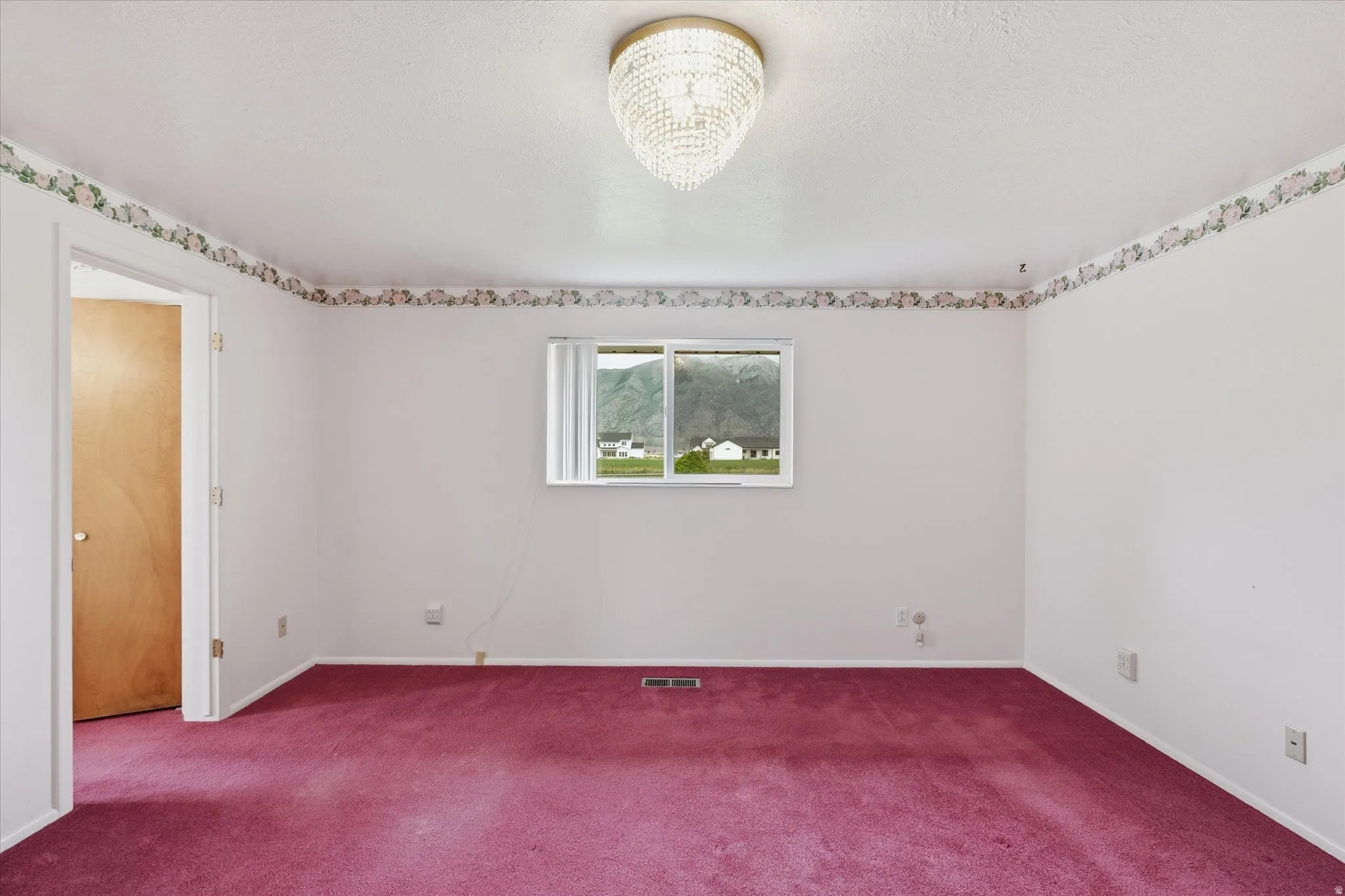 Interior room featuring white walls, a floral border, and a crystal chandelier