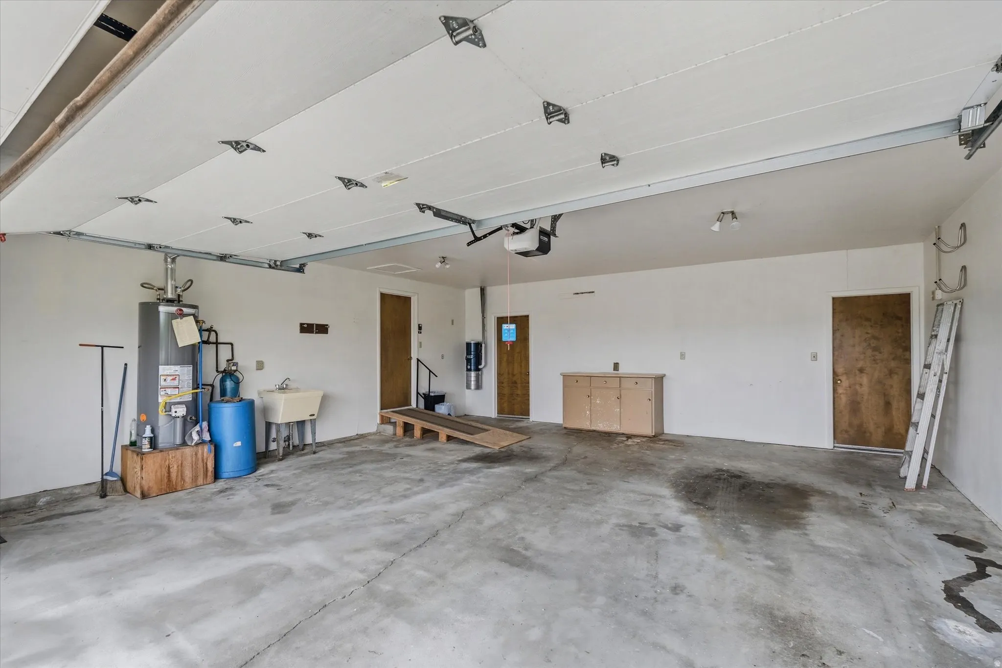 Oversized garage featuring a concrete floor, utility sink, and ample overhead lighting