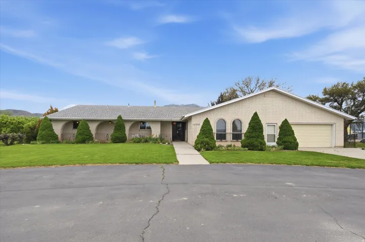 Ranch-style residence featuring a light-colored brick exterior, a grey shingle roof, and an attached two-car garage