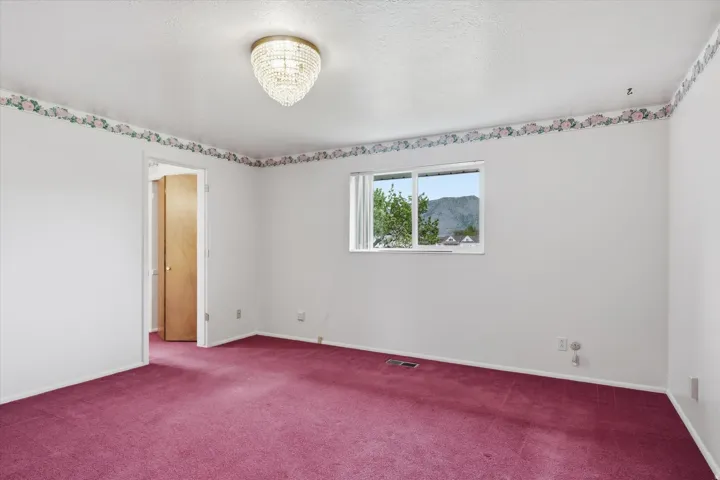 Suite room featuring a crystal chandelier, wall-to-wall carpeting, white painted walls, a window with mountain scenery, and a solid wood door