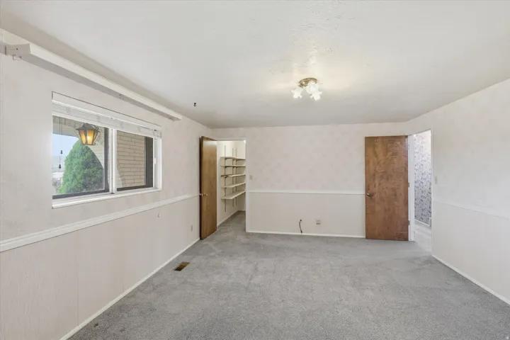Interior room featuring light gray carpeting, wainscoting, and patterned wallpaper