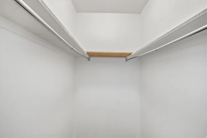 White-painted closet featuring built-in shelving and hanging rods