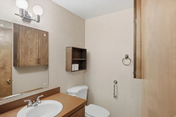 Bathroom featuring a vanity with an integrated sink, wall-mounted mirror, and overhead double light fixture