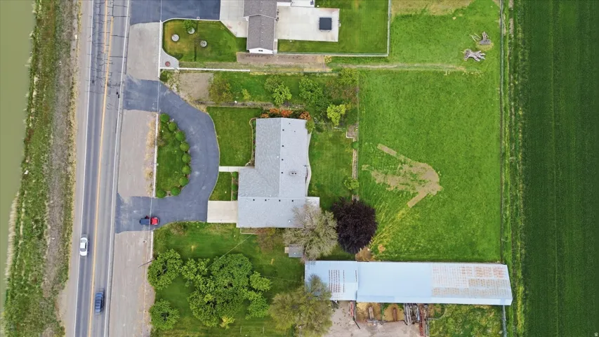 Large lot featuring a main residence with a gray shingle roof, a paved driveway, and a large metal-roofed outbuilding