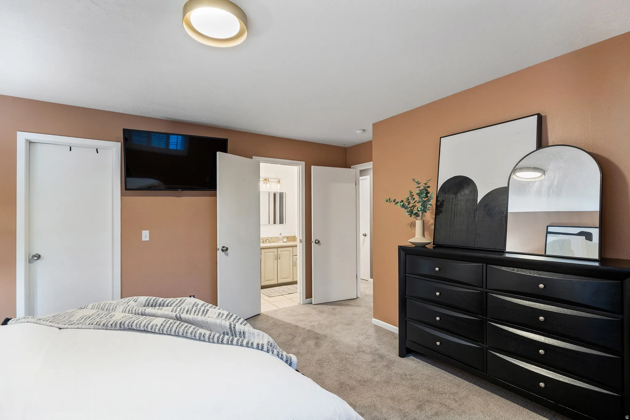 Carpeted room featuring a ceiling-mounted light fixture and a wall-mounted television