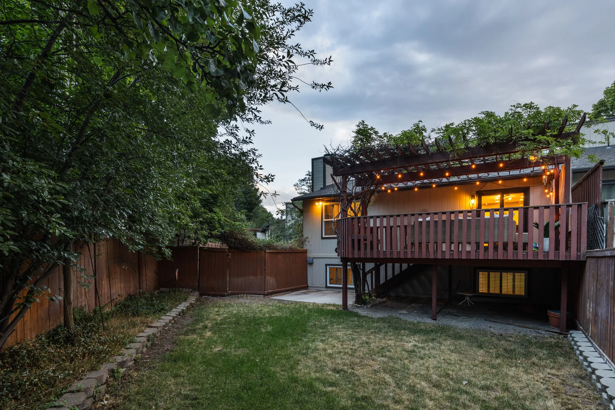 Expansive backyard featuring a manicured lawn, wood fencing, and a stone retaining wall