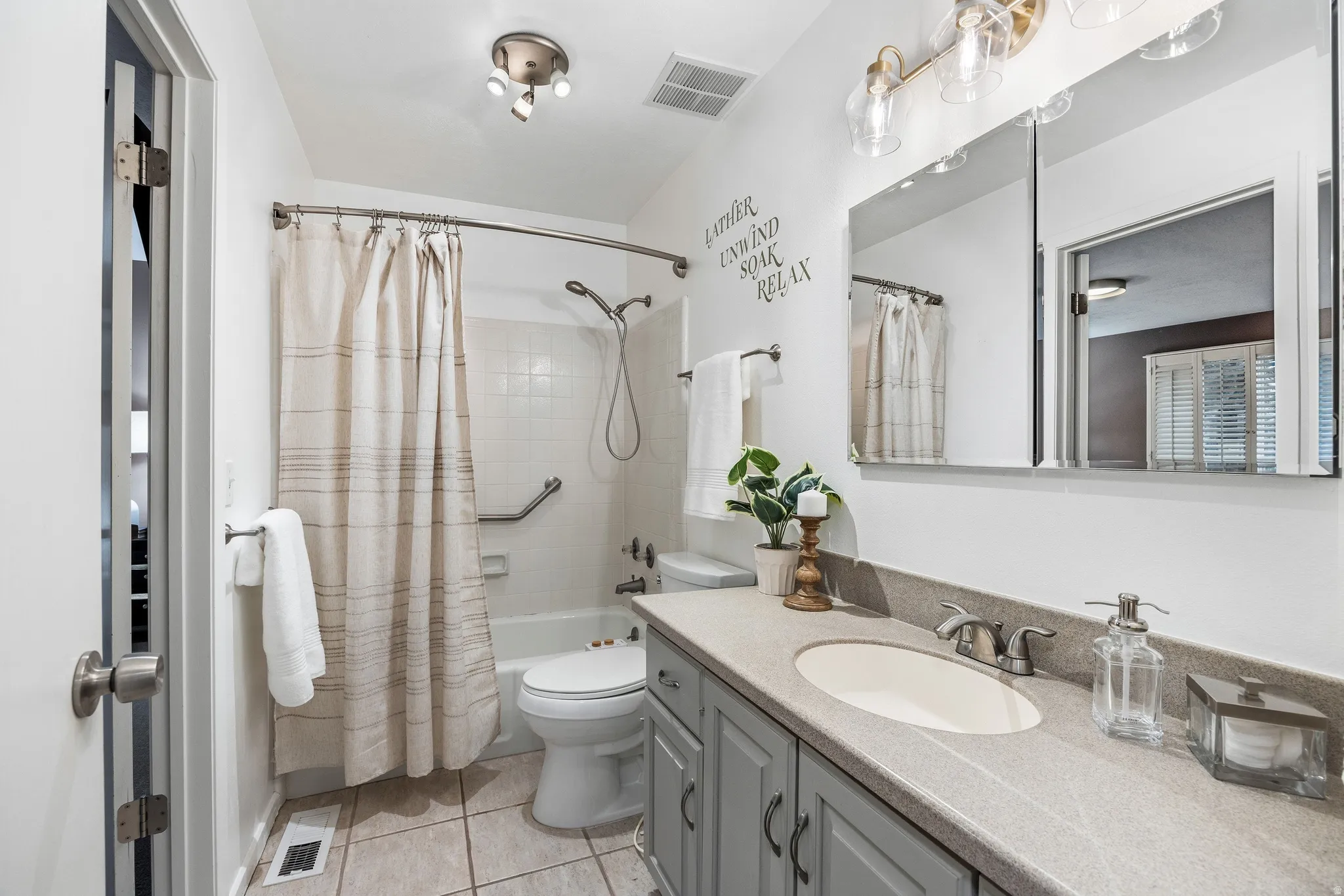 Bathroom featuring a single vanity with a light gray countertop, undermount sink, and light gray cabinet storage