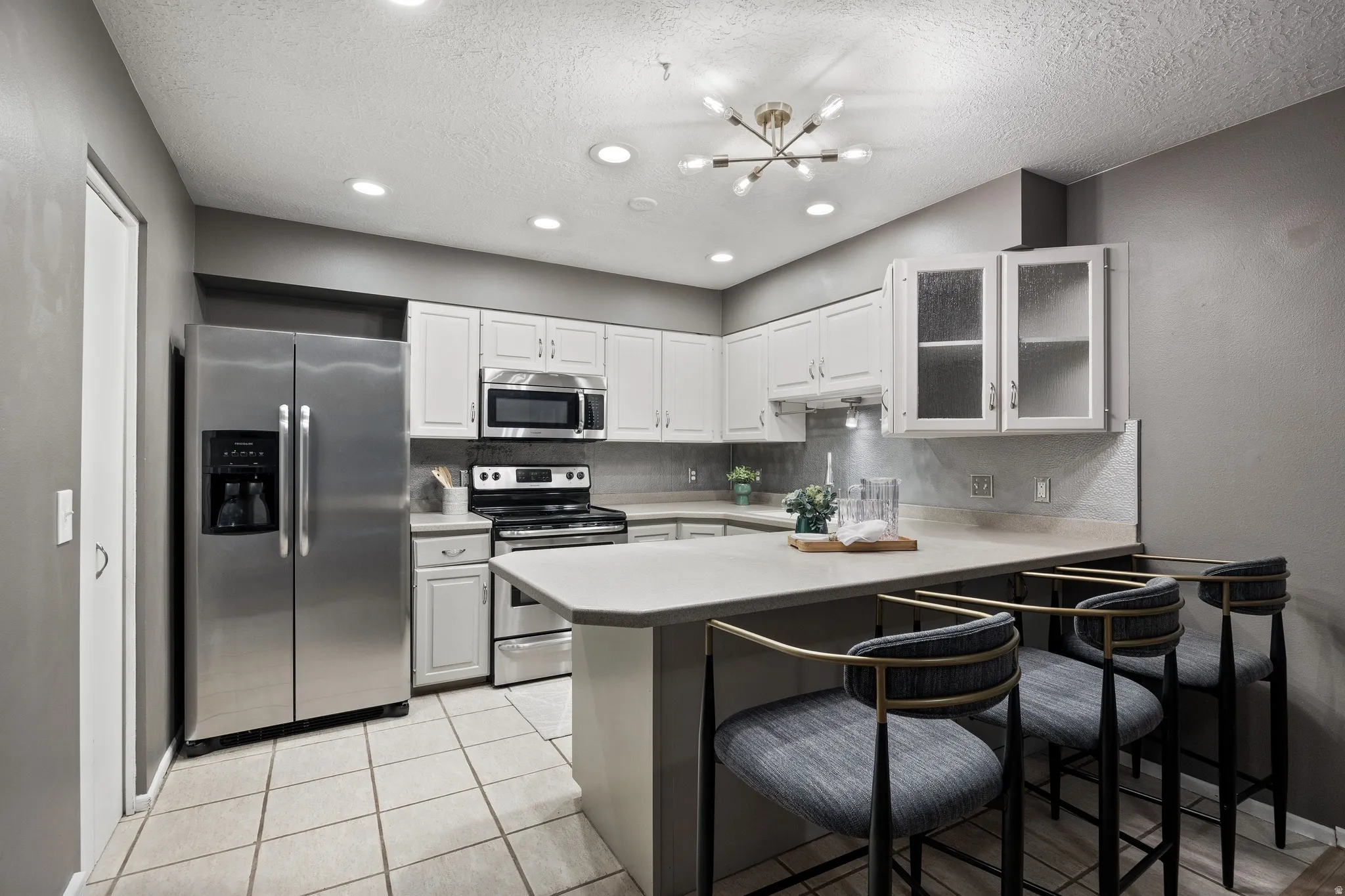 Kitchen featuring stainless steel appliances, white cabinetry, light countertops, a tile backsplash, and recessed lighting