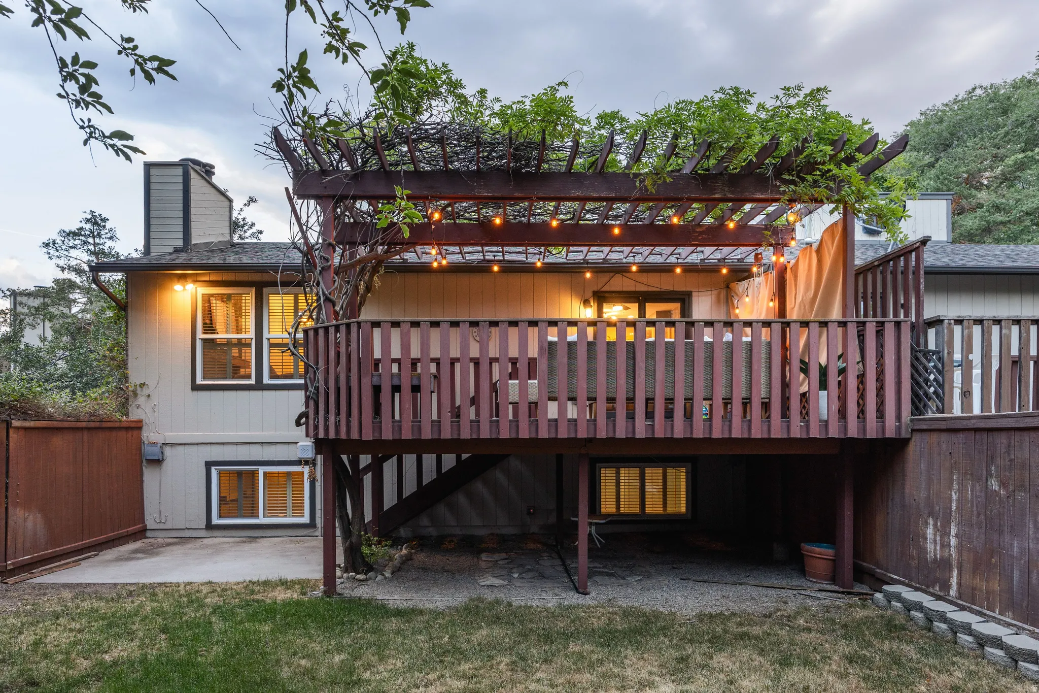 Multi-level deck with a wood pergola, string lights, and a privacy screen