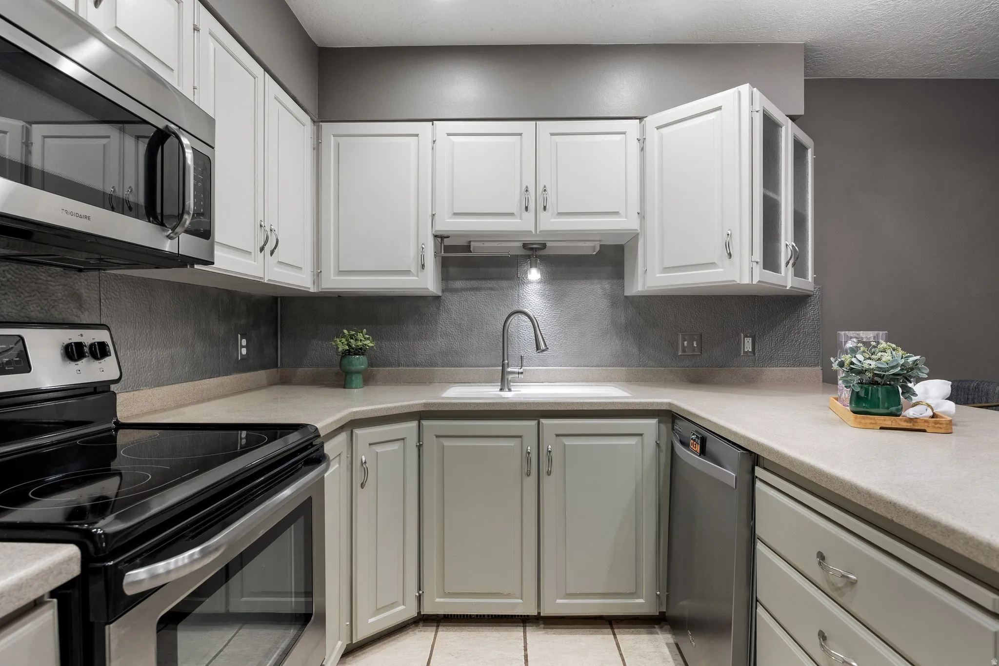 Kitchen featuring light cabinetry, stainless steel appliances, and textured backsplash
