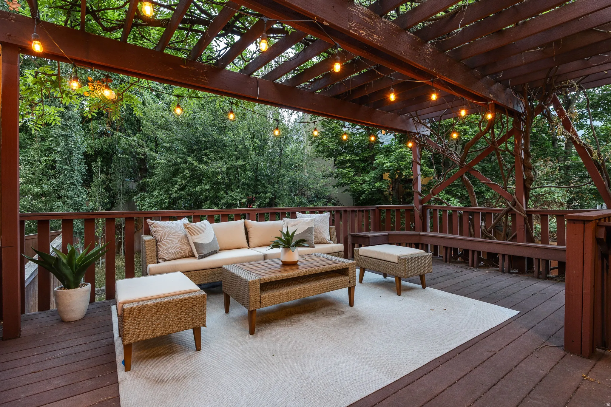 Spacious wood deck featuring a pergola, built-in string lighting, and integrated bench seating
