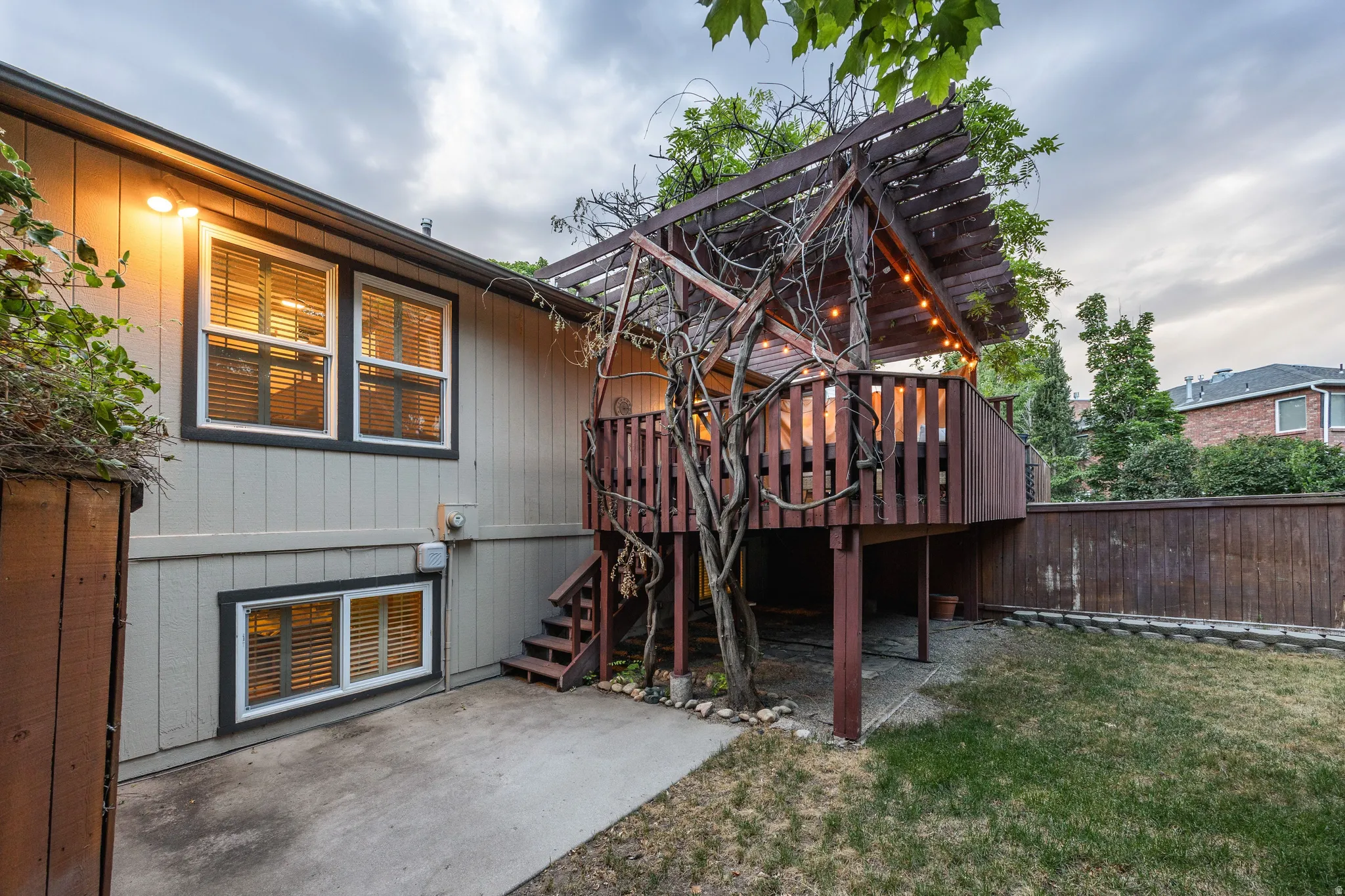 Elevated wood deck with a slatted pergola and string lighting