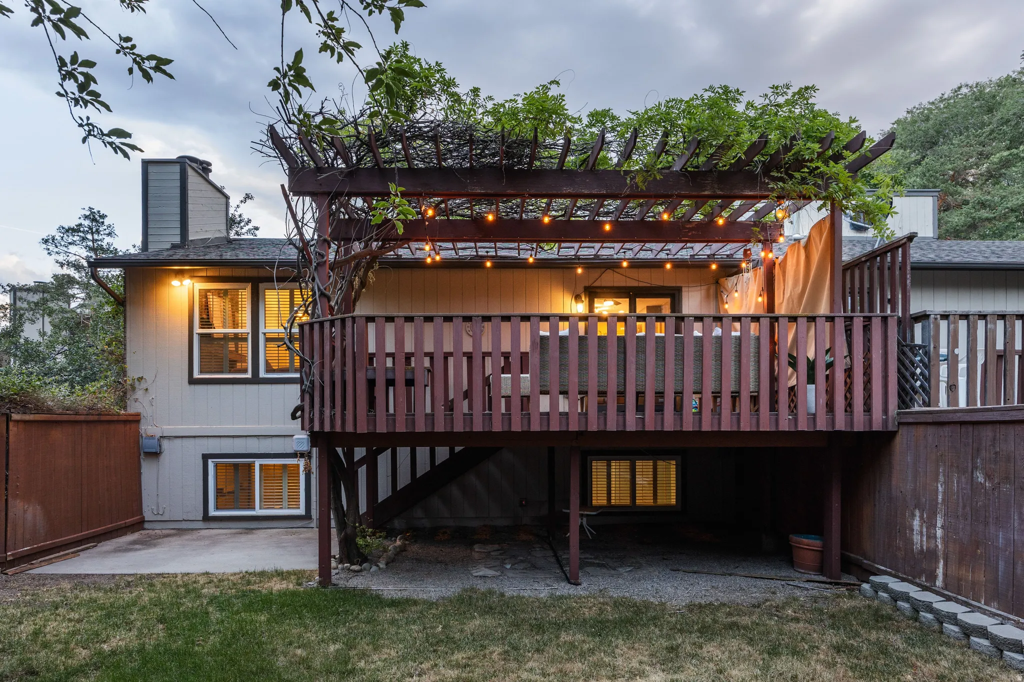 Multi-level deck featuring a pergola with string lights and established greenery