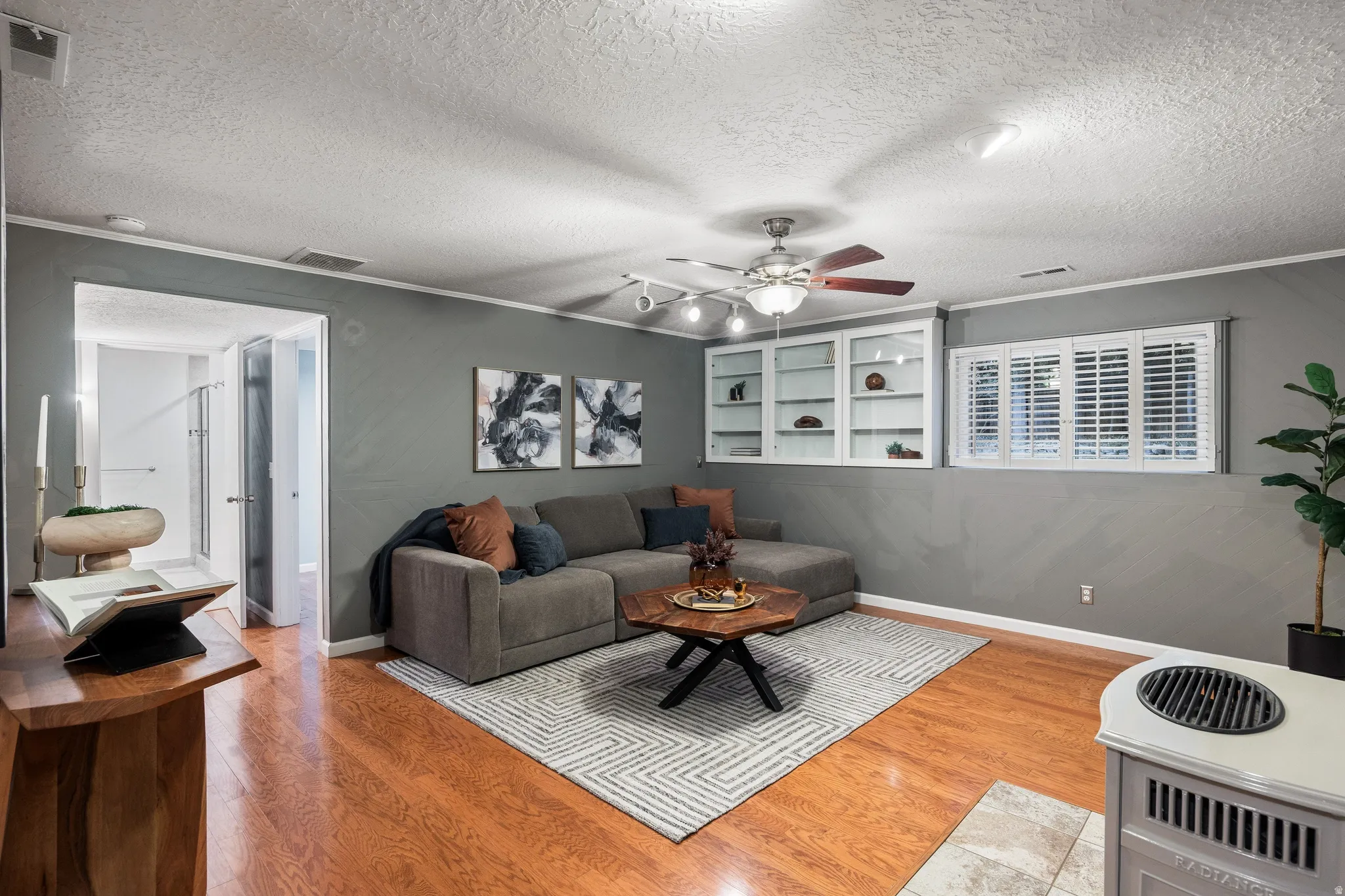 Wood-finish flooring throughout a spacious room with a ceiling fan