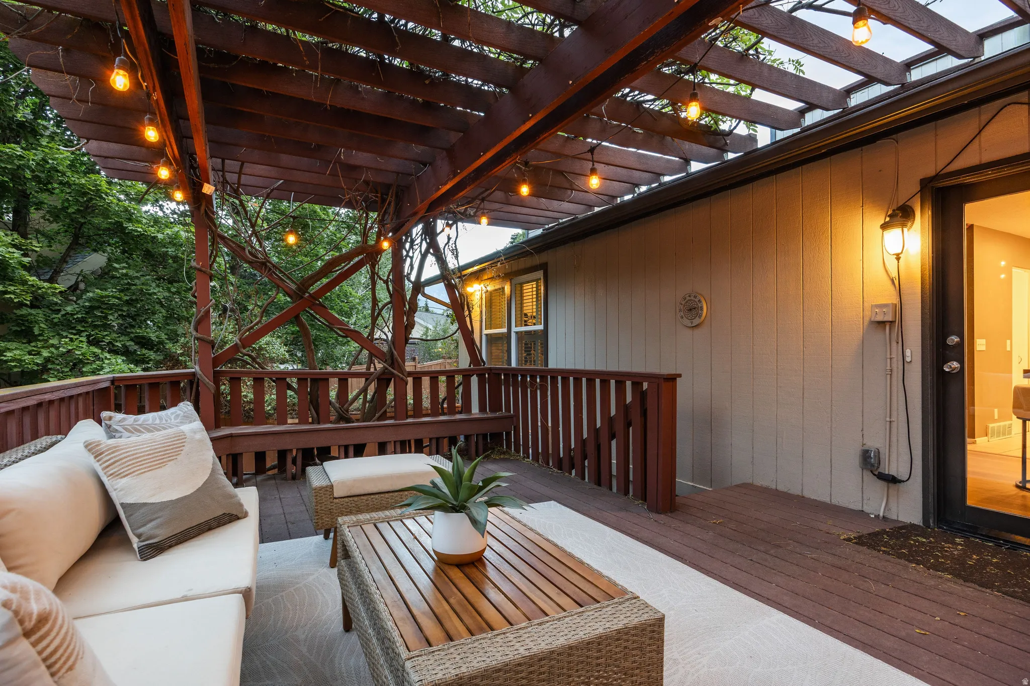 Spacious outdoor deck featuring a wood pergola with string lighting, built-in bench seating, and wood-panel siding