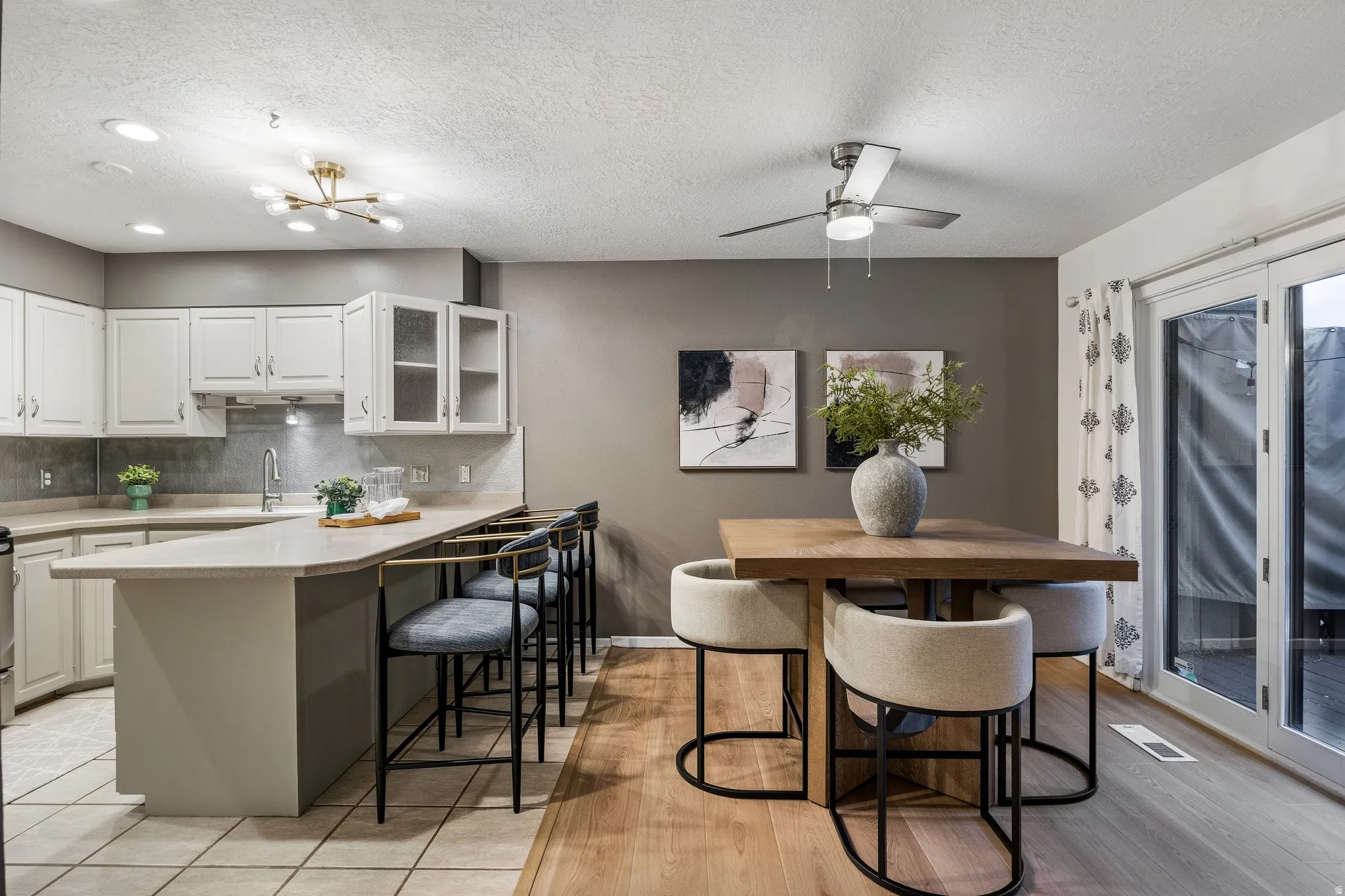 Open-concept kitchen and dining area featuring white cabinetry, light-toned countertops, and a tile backsplash