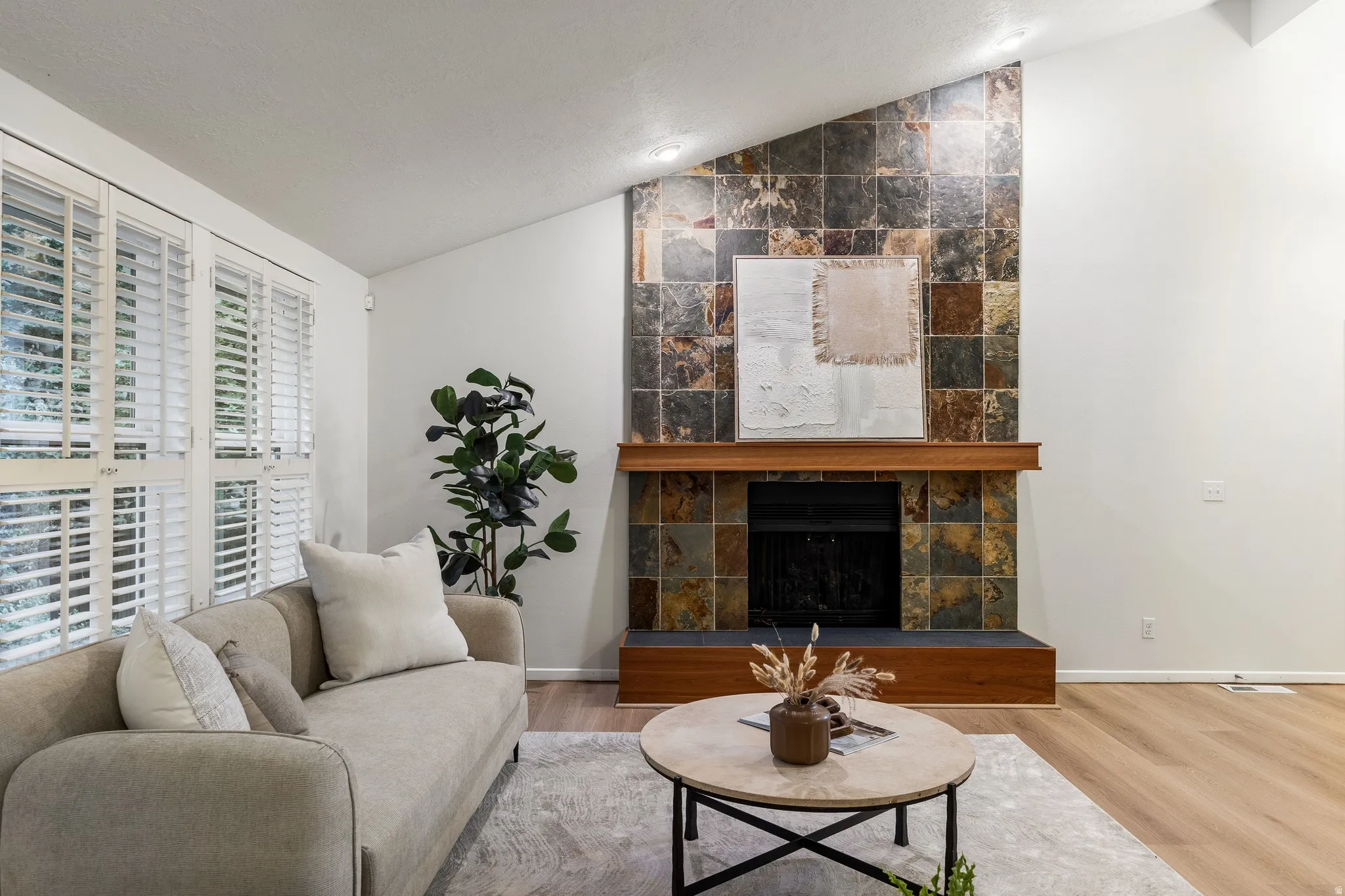 Living area featuring a floor-to-ceiling fireplace with stone tile surround and a wood mantel