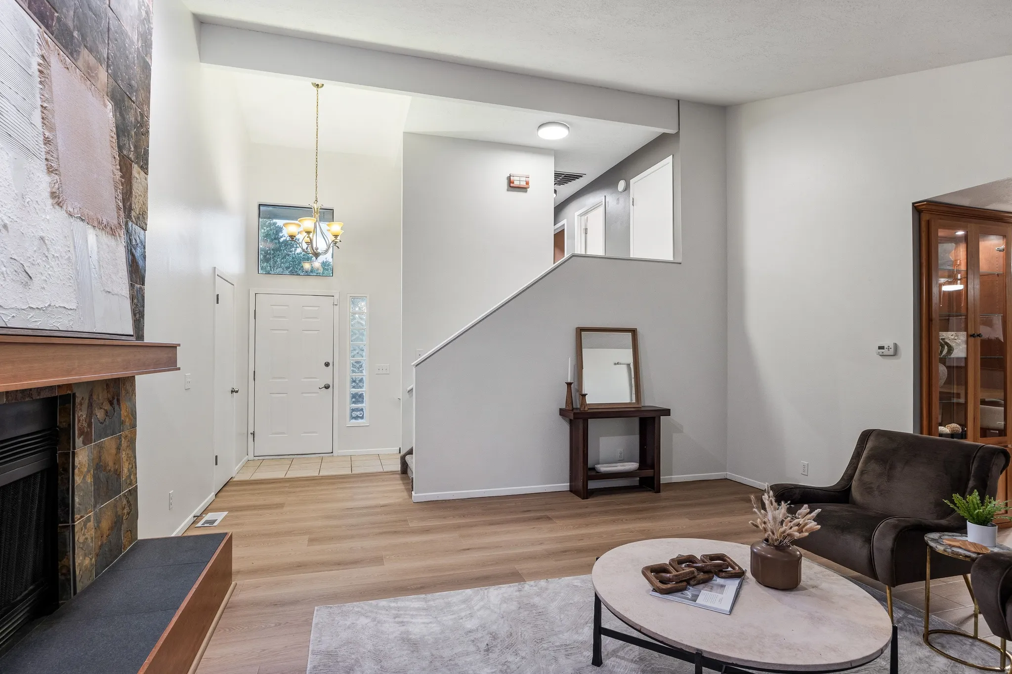 Open living space featuring wood-finish flooring and a stone-clad fireplace with a wood mantle